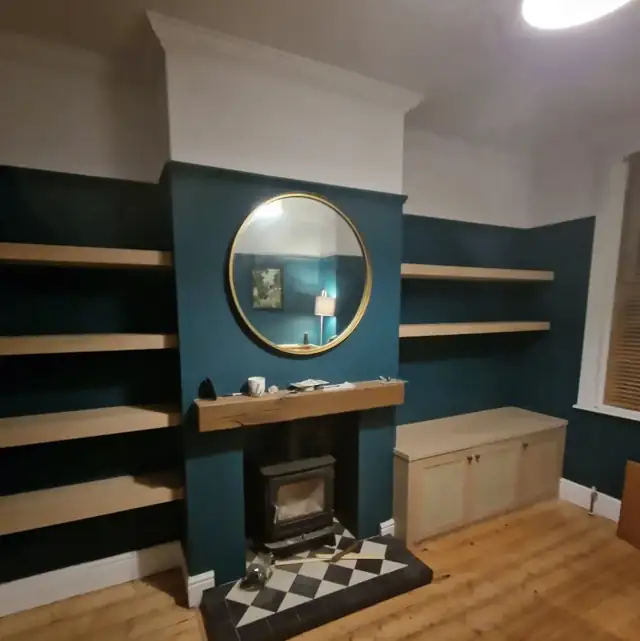 Floating oak shelves and window seat in alcoves beside a fireplace